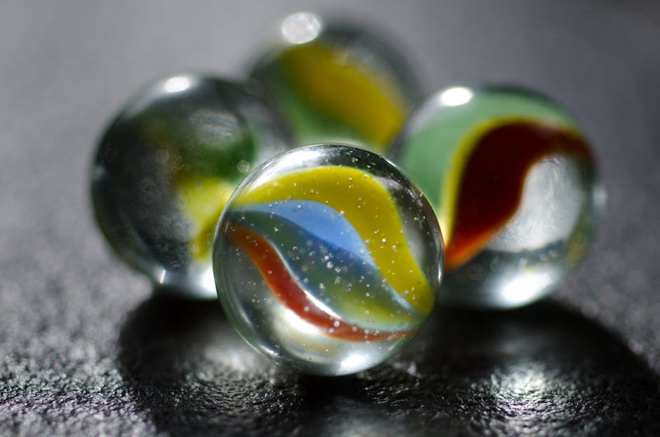Close-up of colorful glass marbles with intricate patterns on a dark surface.